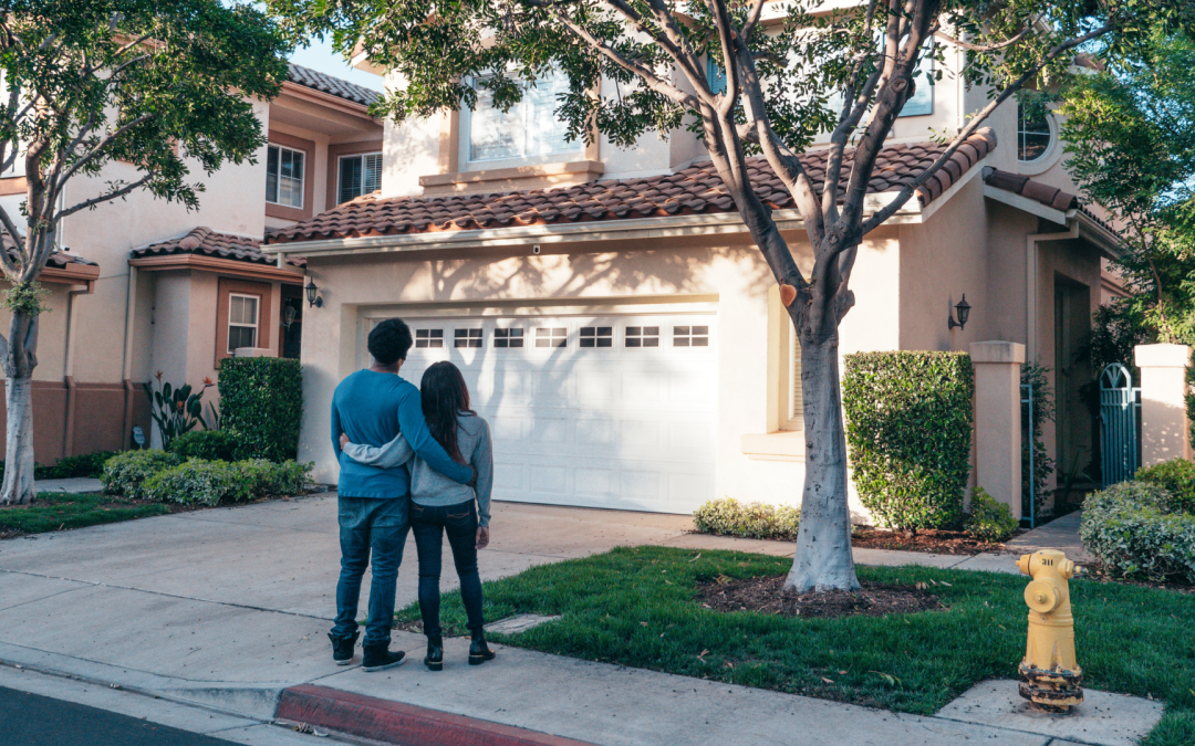 Couple standing in front of a residential home, representing homeowners protecting their property through estate planning and real estate legacy planning in California.
